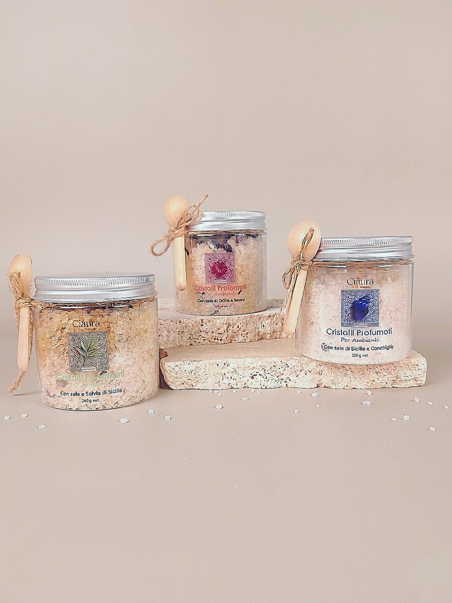 barattolo trasparente in pet che contiene cristalli profumati per ambiente a base di sale di sicilia di trapani e fiori essiccati di ibisco. con tappo in alluminio e  cucchino in legno dosatore
