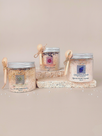 barattolo trasparente in pet che contiene cristalli profumati per ambiente a base di sale di sicilia di trapani e fiori essiccati di ibisco. con tappo in alluminio e  cucchino in legno dosatore